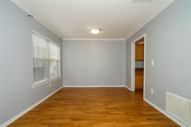 spare room featuring hardwood / wood-style flooring and crown molding