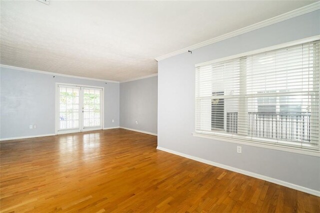 empty room with ornamental molding, light hardwood / wood-style flooring, and french doors