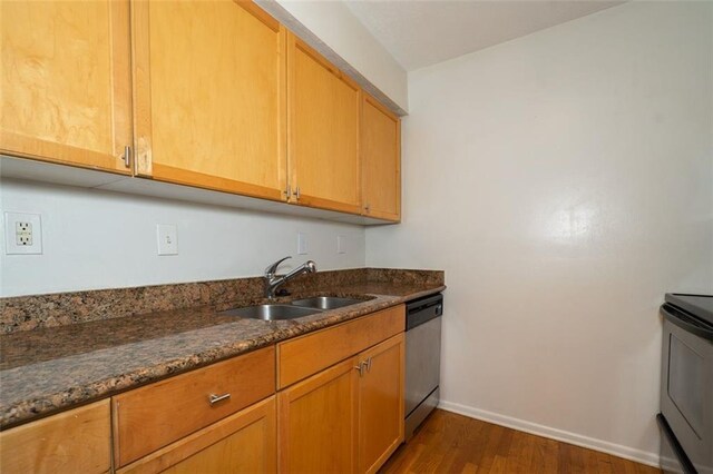 kitchen featuring sink, dishwasher, dark stone counters, dark hardwood / wood-style flooring, and stove