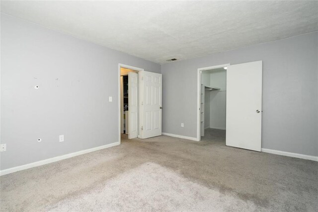 unfurnished bedroom featuring a closet, a spacious closet, and carpet