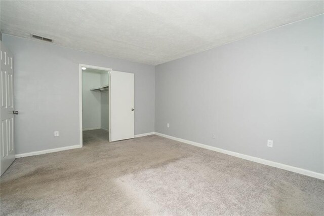 unfurnished bedroom with a spacious closet, a closet, and carpet flooring