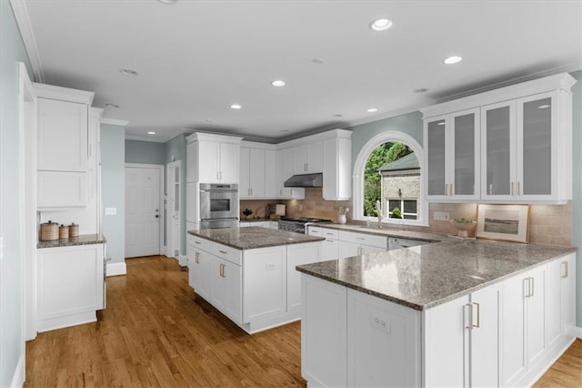 745 Glengate Pl, Atlanta, GA 30328 - kitchen with under cabinet range hood, crown molding, white cabinets, glass insert cabinets, and wood finished floors