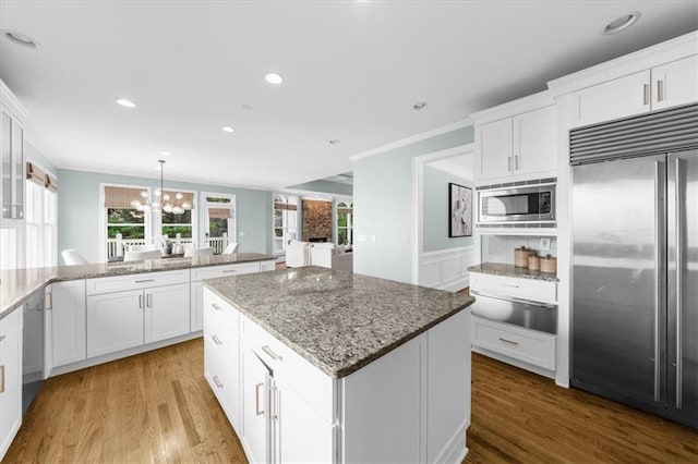 745 Glengate Pl, Atlanta, GA 30328 - kitchen featuring built in appliances, a warming drawer, a kitchen island, wood finished floors, and ornamental molding