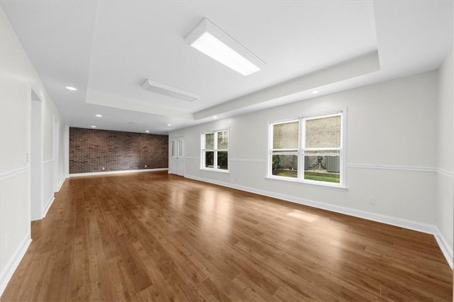 745 Glengate Pl, Atlanta, GA 30328 - unfurnished living room with a raised ceiling, brick wall, wood finished floors, and recessed lighting