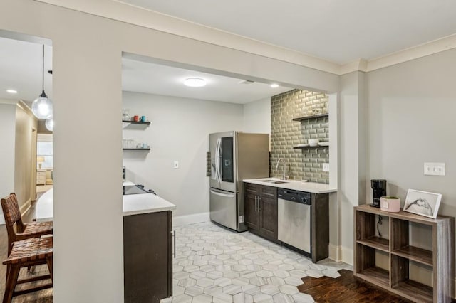 kitchen with sink, appliances with stainless steel finishes, hanging light fixtures, dark brown cabinetry, and ornamental molding