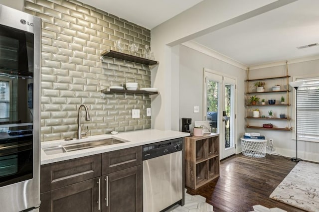 kitchen featuring sink, dark brown cabinets, stainless steel appliances, tasteful backsplash, and dark hardwood / wood-style flooring