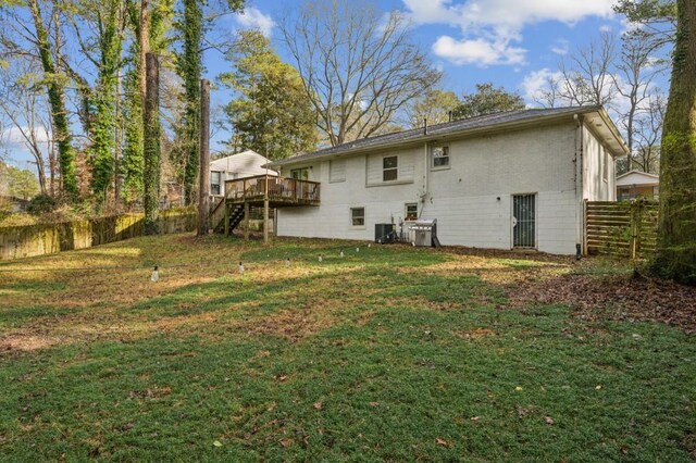 rear view of house featuring a wooden deck and a lawn