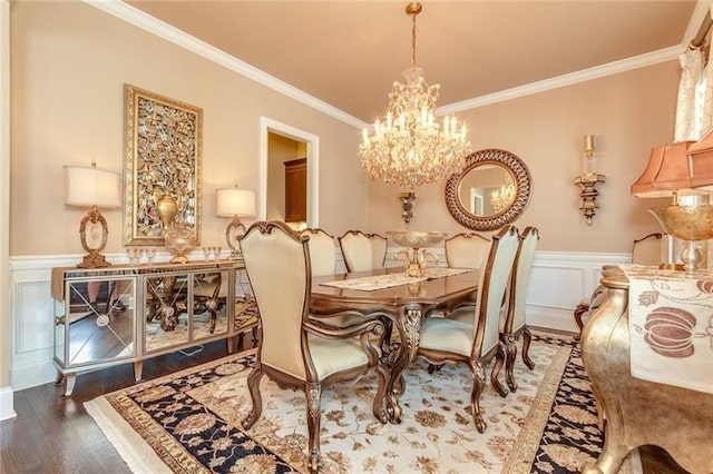 dining area featuring ornamental molding, dark wood finished floors, a notable chandelier, and wainscoting