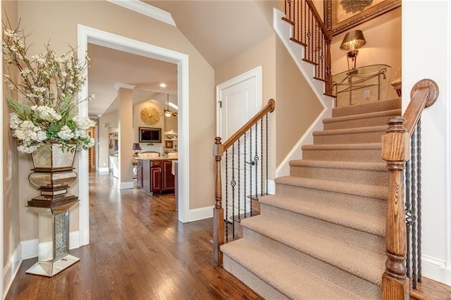 staircase featuring vaulted ceiling, baseboards, and wood finished floors