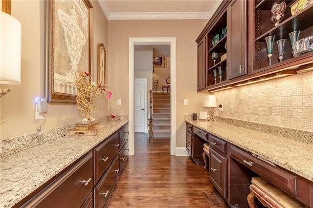 bar with dark wood-style flooring, baseboards, backsplash, built in study area, and crown molding