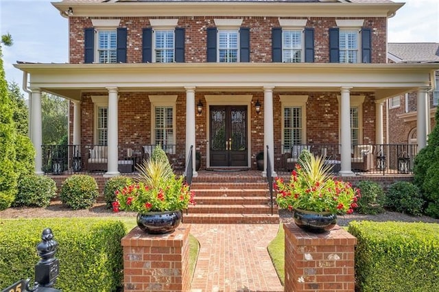 view of front of home featuring brick siding, a porch, and french doors