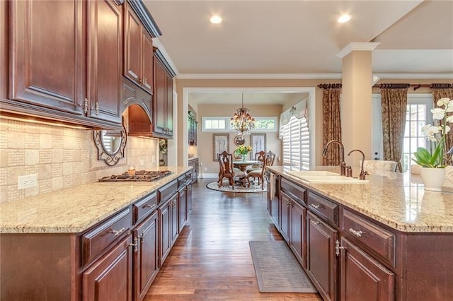 kitchen featuring stainless steel gas cooktop, tasteful backsplash, ornamental molding, dark wood-type flooring, and a sink