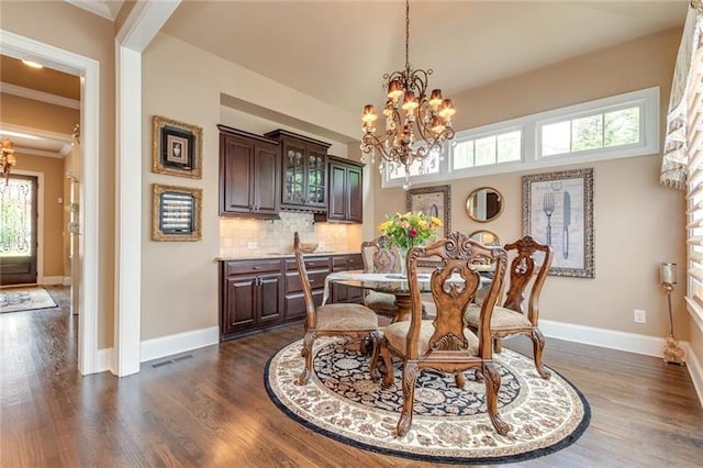 dining space featuring a chandelier, dark wood-type flooring, crown molding, and baseboards