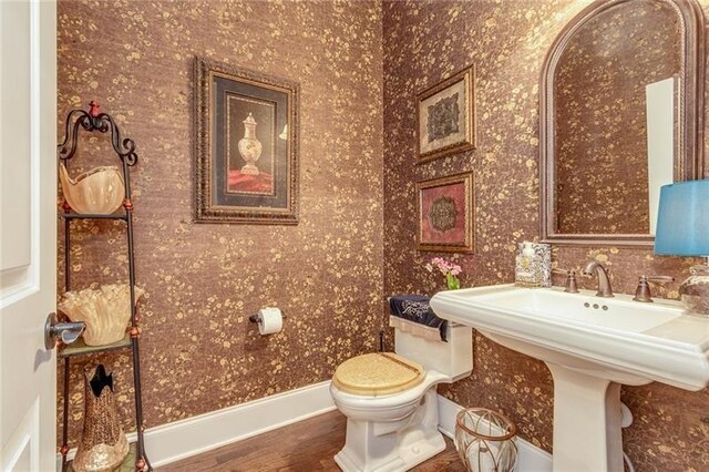 bathroom with toilet, baseboards, a sink, and wood finished floors