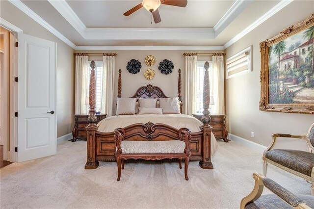 bedroom with ornamental molding, a raised ceiling, and light carpet