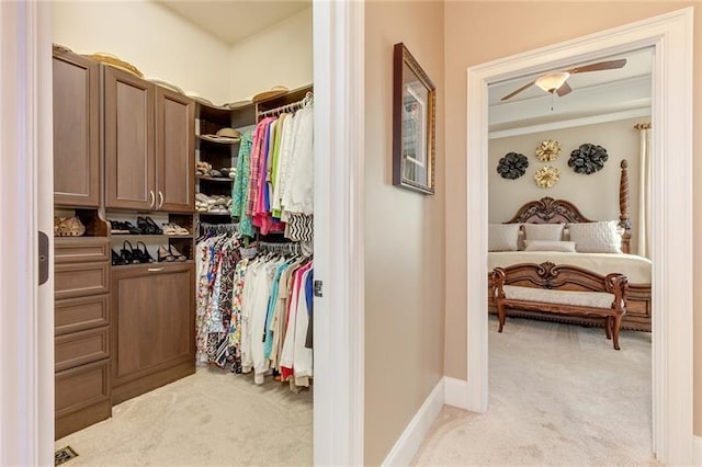 spacious closet with a ceiling fan and light carpet