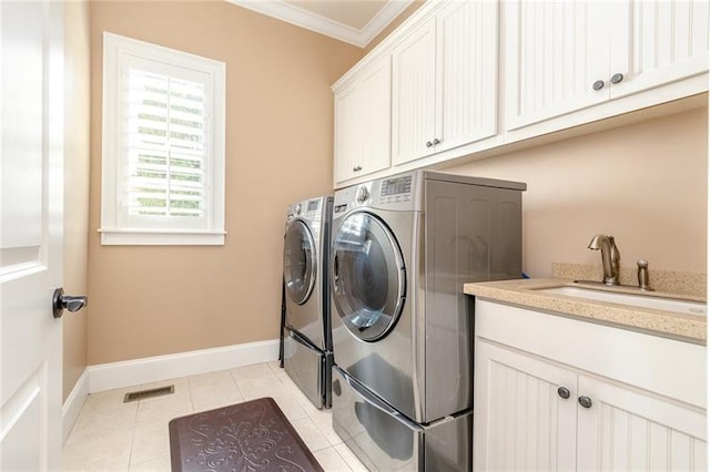 washroom featuring light tile patterned flooring, a sink, ornamental molding, independent washer and dryer, and cabinet space