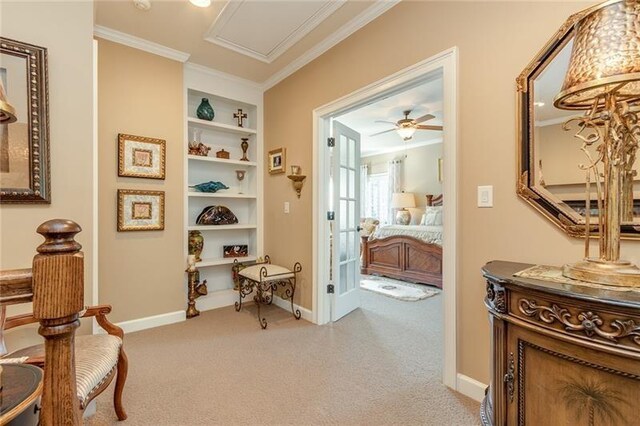 hallway with light carpet, ornamental molding, built in features, and baseboards