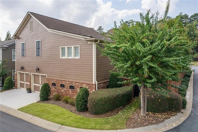 view of property exterior with driveway, brick siding, and an attached garage