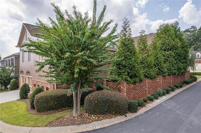 view of side of home featuring driveway and fence