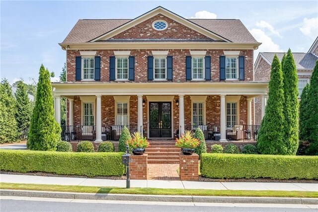 view of front of property featuring french doors, a porch, and brick siding