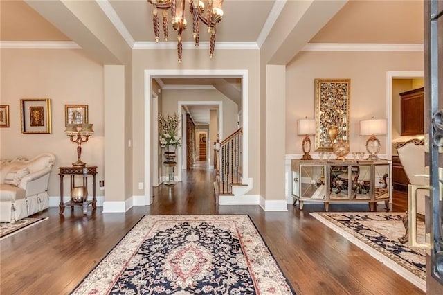 entrance foyer featuring a chandelier, dark wood-type flooring, baseboards, stairs, and crown molding