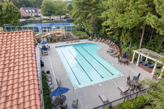 view of pool with a tennis court, a patio area, and fence