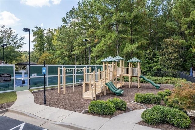 community play area featuring a tennis court and fence