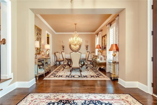 dining space with crown molding, dark wood-type flooring, baseboards, and an inviting chandelier