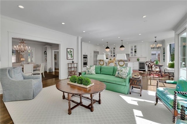 living room featuring an inviting chandelier, crown molding, dark wood-type flooring, and wine cooler