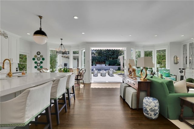 kitchen featuring sink, dark wood-type flooring, white cabinetry, a notable chandelier, and decorative light fixtures