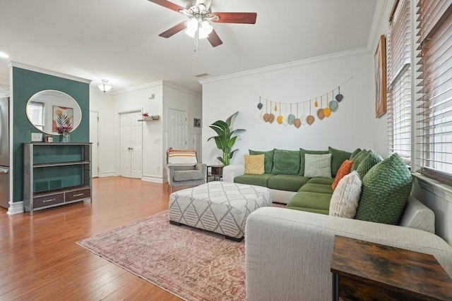 living room featuring crown molding, a ceiling fan, baseboards, and wood finished floors