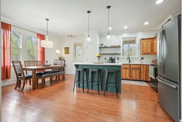 kitchen with plenty of natural light, freestanding refrigerator, and ornamental molding