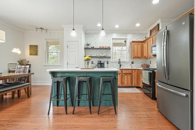 kitchen with crown molding, appliances with stainless steel finishes, a sink, and a wealth of natural light