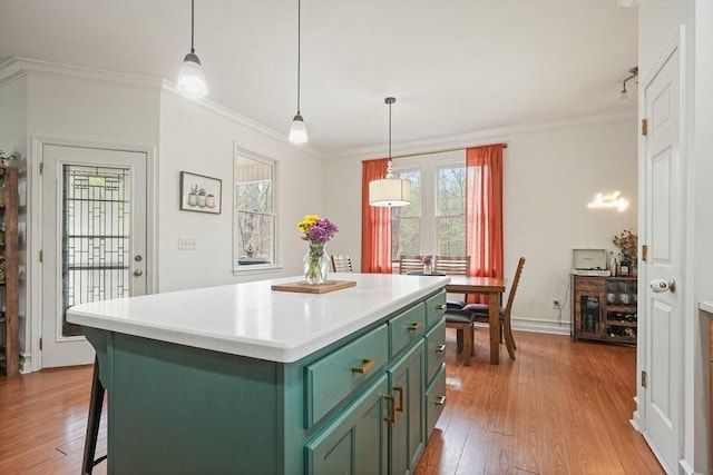 kitchen featuring crown molding, a center island, green cabinets, and wood finished floors