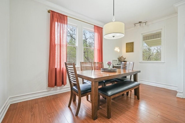 dining room with a healthy amount of sunlight, baseboards, ornamental molding, and wood finished floors