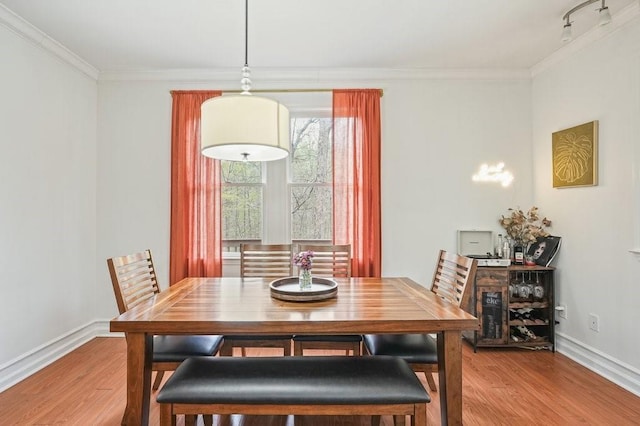 dining area with baseboards, ornamental molding, and light wood-style flooring