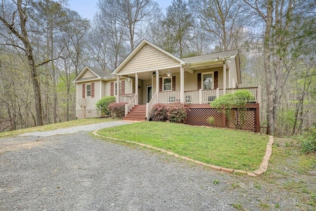 view of front of house featuring a porch, ceiling fan, a front yard, and gravel driveway