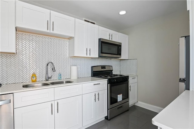 kitchen featuring white cabinetry, sink, stainless steel appliances, dark tile patterned floors, and backsplash