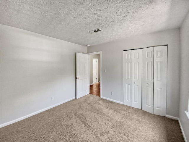 unfurnished bedroom featuring a textured ceiling, dark carpet, and a closet