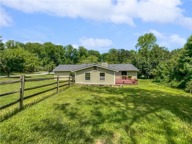 rear view of house with a rural view, a yard, and a wooden deck