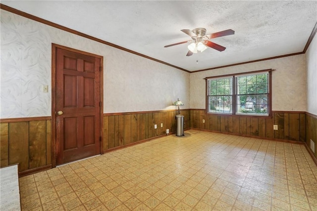 spare room featuring a wainscoted wall, crown molding, a textured ceiling, and tile patterned floors