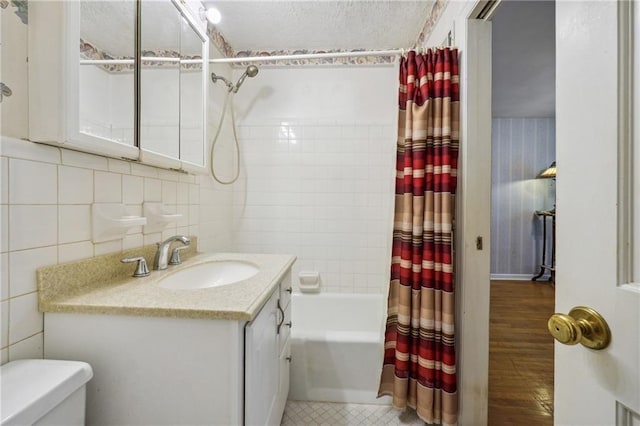 bathroom with shower / bath combo, toilet, a textured ceiling, vanity, and tile walls