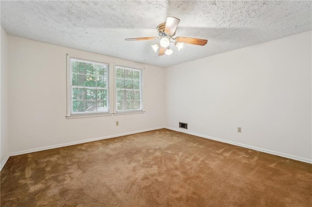 empty room with a textured ceiling, carpet floors, visible vents, and baseboards