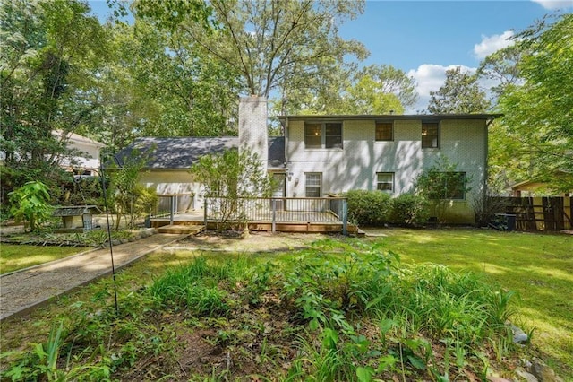 view of front facade with a deck, a chimney, a front yard, and fence