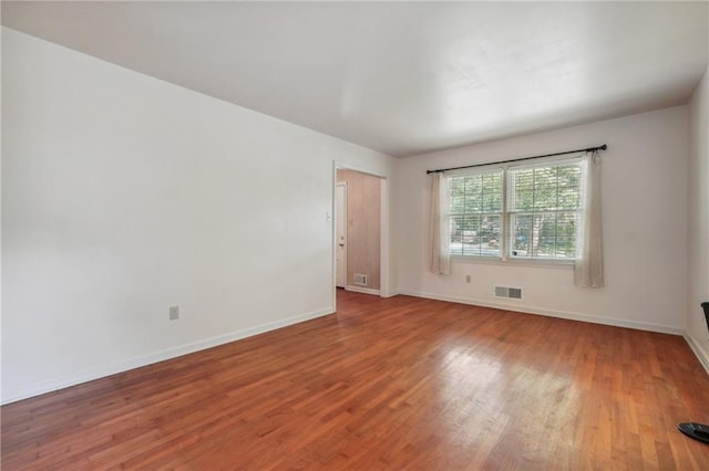 unfurnished room with visible vents, baseboards, and wood finished floors