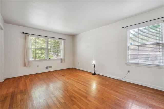 unfurnished room with visible vents, light wood-style flooring, and baseboards