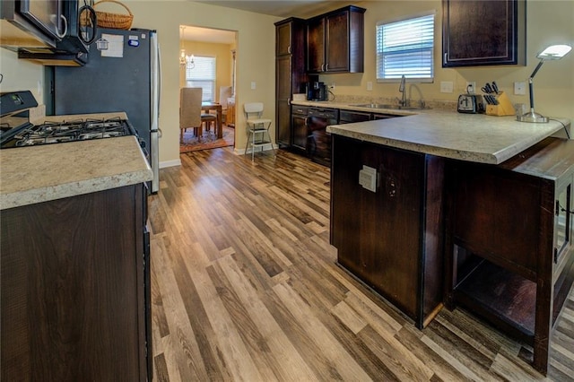 110 Baltusrol Way, Covington, GA 30014 - kitchen featuring black appliances, a chandelier, dark brown cabinets, light wood finished floors, and a sink