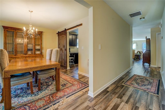 110 Baltusrol Way, Covington, GA 30014 - dining room with a barn door, wood finished floors, a chandelier, and baseboards