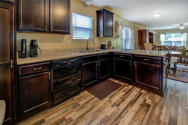 110 Baltusrol Way, Covington, GA 30014 - kitchen with black dishwasher, a sink, a peninsula, light countertops, and light wood finished floors